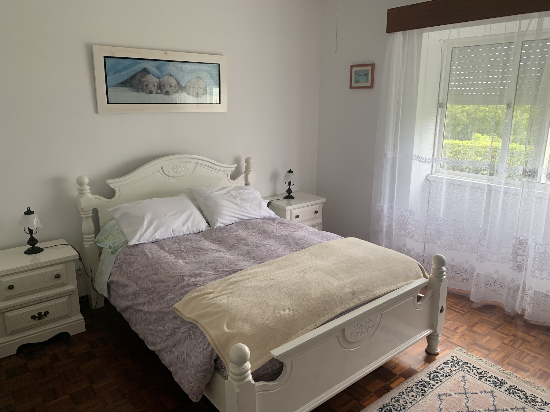 Simple bright bedroom with white double bed and wood flooring